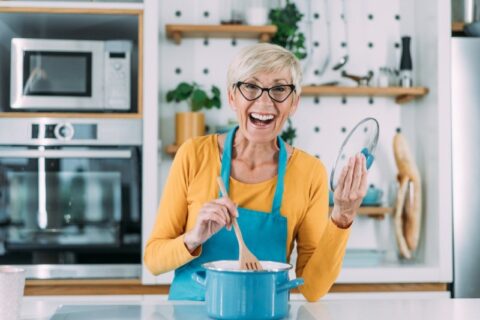 Person cooking in a modern kitchen with white cabinets and a blue pot on a granite countertop in Durango, CO