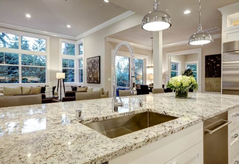 Modern kitchen island with polished granite countertop, stainless steel sink, and pendant lights in Durango, CO