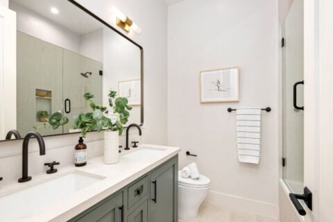 Modern bathroom with double vanity, white quartz countertop, black fixtures, and glass shower in Durango, CO